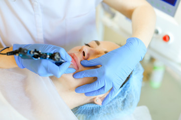 Close up hands in latex gloves making lip tattoo with microblading device. Concept of beauty salon,...