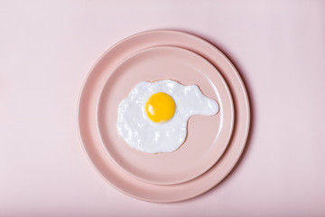 Fried eggs on the plate on a beige background. Flat lay, top. Laconic