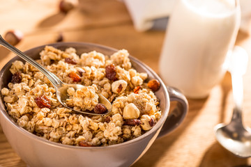 Morning granola breakfast with raisins, cranberries and hazelnuts served with almond milk on a wooden table
