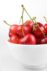 Bowl containing cherries on white background