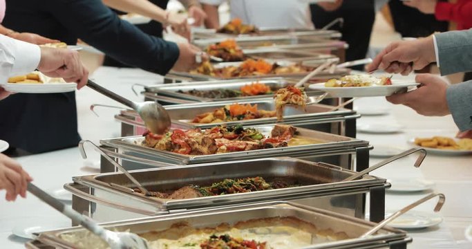 People group catering buffet food indoor in luxury restaurant with meat colorful fruits and vegetables. Close up. Banquet, lunch, bad nutrition, gluttony concept