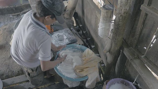 Close-up on man filling noodle pressing machine with rice dough