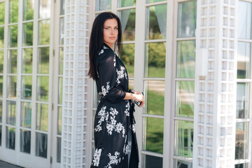 A beautiful stylish business lady is dressed in silk clothes, she came to an important meeting in a restaurant with a veranda and stained glass walls. Concept of people, business, business meeting.