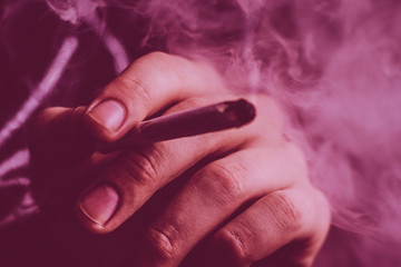 cannabis weed A man smokes, a joint and a lighter in his hands. Smoke on a black background....
