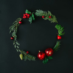 Fototapeta na wymiar Creative Christmas round frame or wreath made with natural winter evergreen tree branches and red berries. Flat lay. Nature concept.