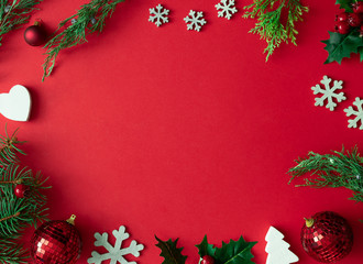 Red Christmas background with winter decoration, tree branches and leaves. Holiday copy space layout.