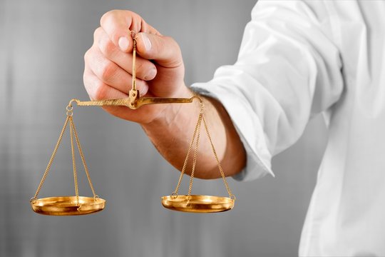 Male hand holding golden scales on dark