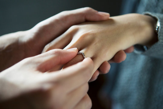 彼女に指輪をはめる20代男性