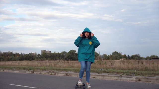 young stylish hipster girl with longboard and a hoodie thumbs up 'ing  