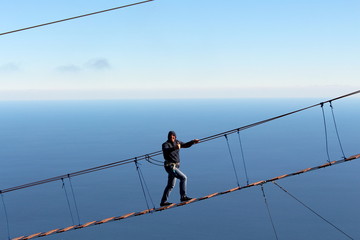 a man climbs the suspension bridge at an altitude of more than 1200 meters above sea level