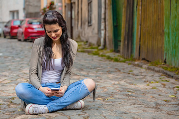 Cute young woman using cellphone in urban surroundings.