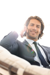 business man talking on a smartphone while sitting in a comfortable chair.