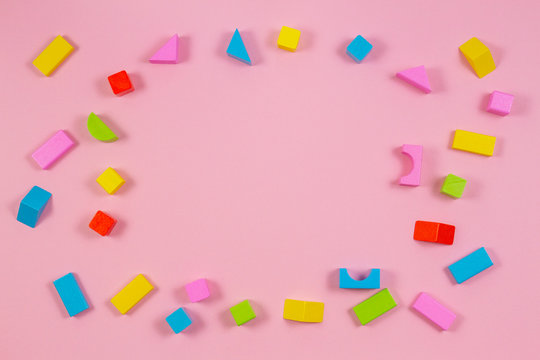 Colorful wooden building blocks on pink background