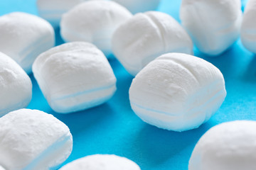 Close-up of white brittle mint sweets or peppermint candy on a blue background