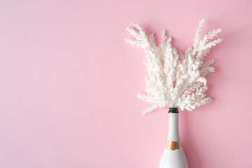 Champagne bottle with snow white Christmas decoration. New Year party greeting card pink background. Minimal style. Flat lay composition.