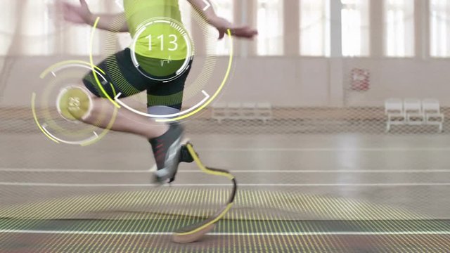 Tracking shot of paralympic athlete with prosthetic leg running on track; digitally animated pulse and speed projections appearing on his knee and hip