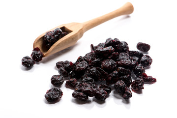 Close-up of pile dried, raw blueberries in a wooden spoon on white background