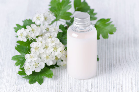 a cosmetic bottle with fresh flowers, selective focus