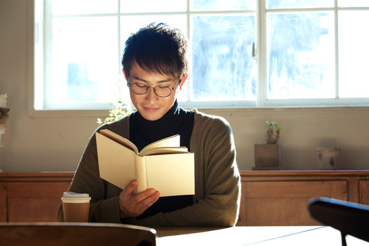 部屋で読書をする20代男性
