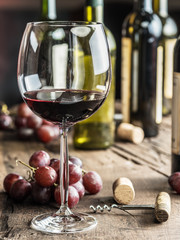 Glass of red wine on the table. Wine bottle and grapes at the background. © volff