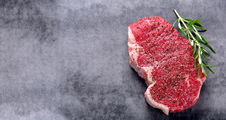 Raw steak with spices on a stone background