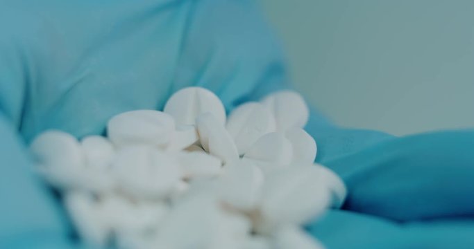 Close up of a scientist hand holding and showing some white pills in a laboratory. Concept: Scient, chemistry, future. Shot on RED 8K