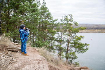 boy standing on a rock and looking through binoculars