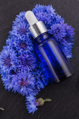 essential oil of cornflower on a dark stone background