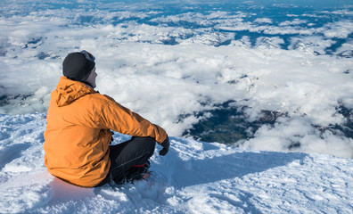 Fototapeta na wymiar Winter hiking. Tourist on snowy mountain top enjoying beautiful view of cloudscape.