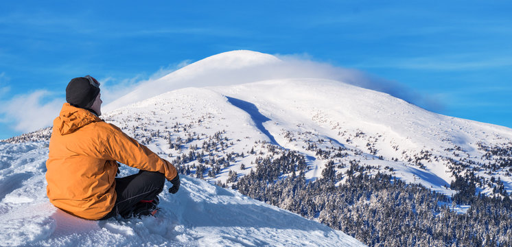 Winter hiking. Tourist on snowy mountain top enjoying beautiful view.