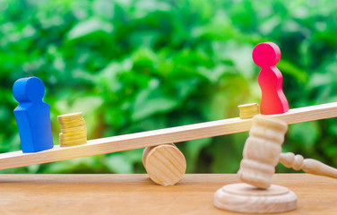 wooden figures of a man and a woman stand on the scales and coins between them. concept of the...