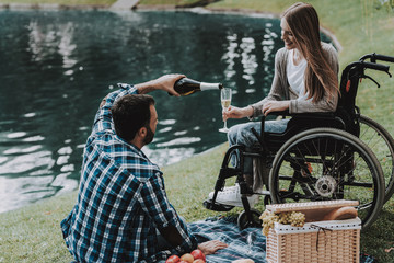 Girl on Wheelchairs with Man on Picnic in Park.
