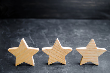 three wooden stars on a black background. The concept of the rating of hotels and restaurants, the evaluation of critics and visitors. Quality level, good service. selective focus