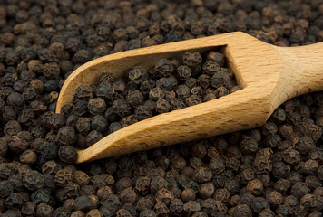 Black pepper scattered with a wooden scoop