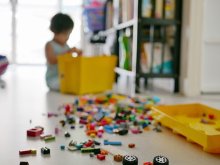 Defocus background of interlocking blocks (toy) being poured and spred out on the floor by little Asian baby girl