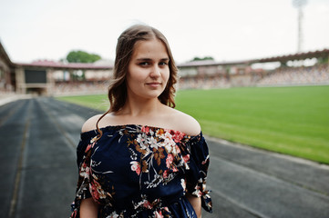 Portrait of a fabulous girl in dress and high heels on the track at the stadium.