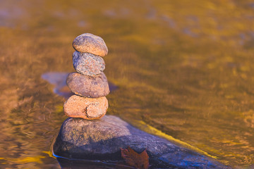 Stacked stone pyramid in front of yellow blurry background with bokeh