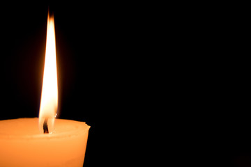 Portrait of one light candle burning brightly on black background. Close-up flame.