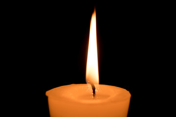 Portrait of one light candle burning brightly on black background. Close-up flame.