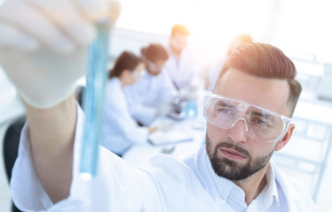 image is blurred. young scientist holding tube with the reagents