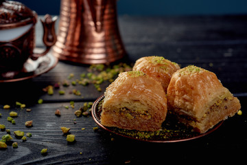 Turkish baklava near walnuts on black wooden background