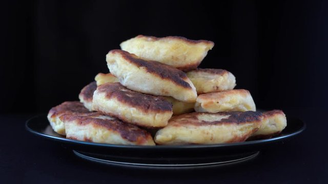 Potato cakes, ukrainian name potato zrazy, stuffed mushrooms or meat or cheese with herbs cream are fried in vegetable oil on black background, close up, rotates. Traditional Ukrainian cuisine