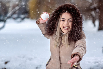 Happy woman playing snowball fight on the snow day. Winter concept..