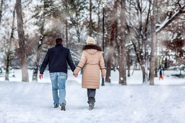 Fototapeta na wymiar Lovers walking in winter snow- Happy Couple in Winter Park having fun..
