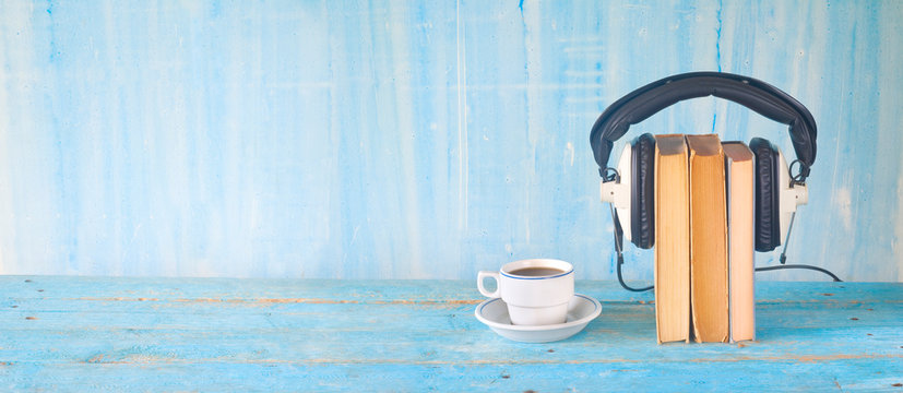 audio book concept, with books, headphones and cup of coffee, panorama, good copy space