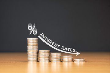 STACKED US QUARTER COINS ON WOODEN TABLE WITH WHITE ILLUSTRATION SHOWS DECREASING OF INTEREST RATES...