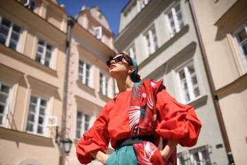 Obraz premium Portrait of a young woman in red clothes posing on the background of old building. Fashion concept