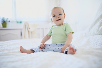 Fototapeta premium Baby girl sitting on bed and laughing