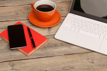 A cup of coffee on the orange plate on the wooden table. Office interior