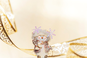 Christmas and New Year winter holiday background in yellow beige color with a garland and a figure of a souvenir snowman with a copy space for writing the text of congratulations